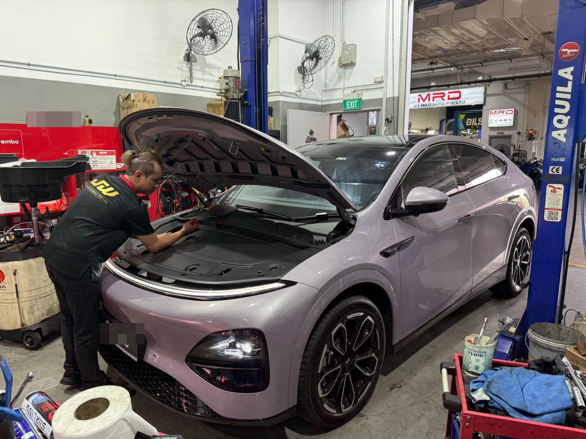 Xpeng G6 EV servicing at JW Motoring Kaki Bukit, Singapore — technician working under the front bonnet during electric vehicle maintenance
