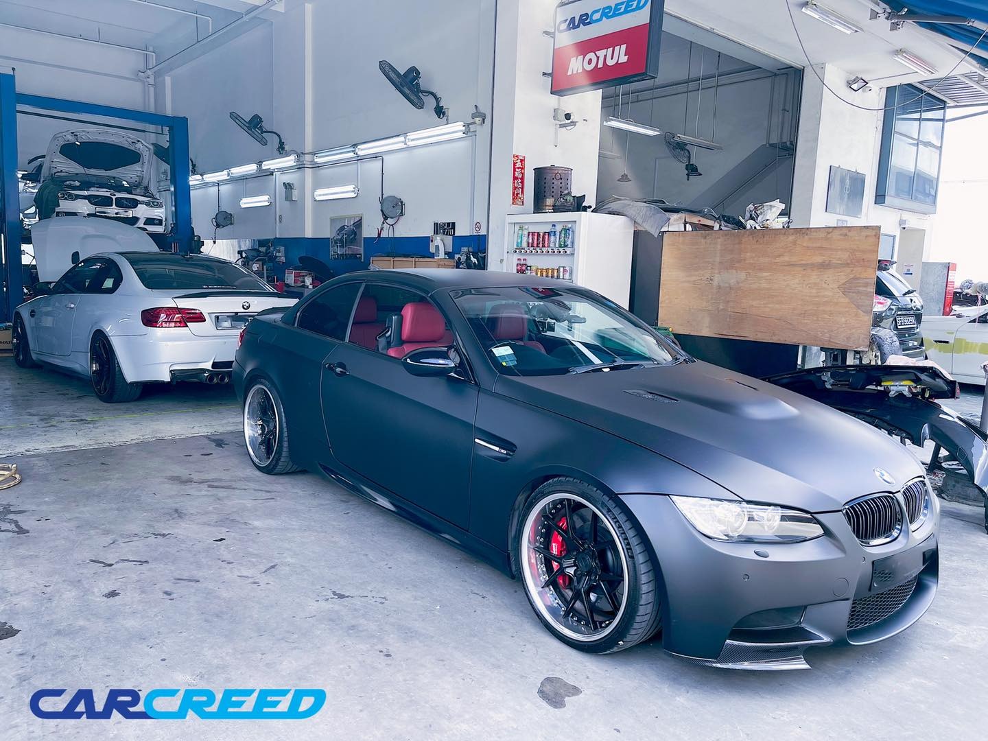 Workshop interior with BMW M3 cars and professional lift equipment during the earlier workshop era